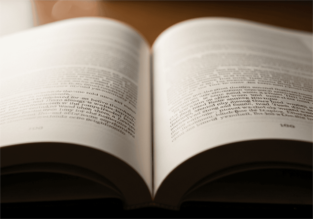 Eine Nahaufnahme eines aufgeschlagenen Romans in warmen Farbtönen, die die reiche Textur des weißen Naturpapiers und den klar lesbaren Text hervorhebt und eine gemütliche und intellektuelle Stimmung erzeugt Eine Nahaufnahme eines aufgeschlagenen Romans in warmen Farbtönen, die die reiche Textur des weißen, ungestrichenen Papiers und den gestochen scharfen, lesbaren Text hervorhebt und eine gemütliche und intellektuelle Stimmung erzeugt.