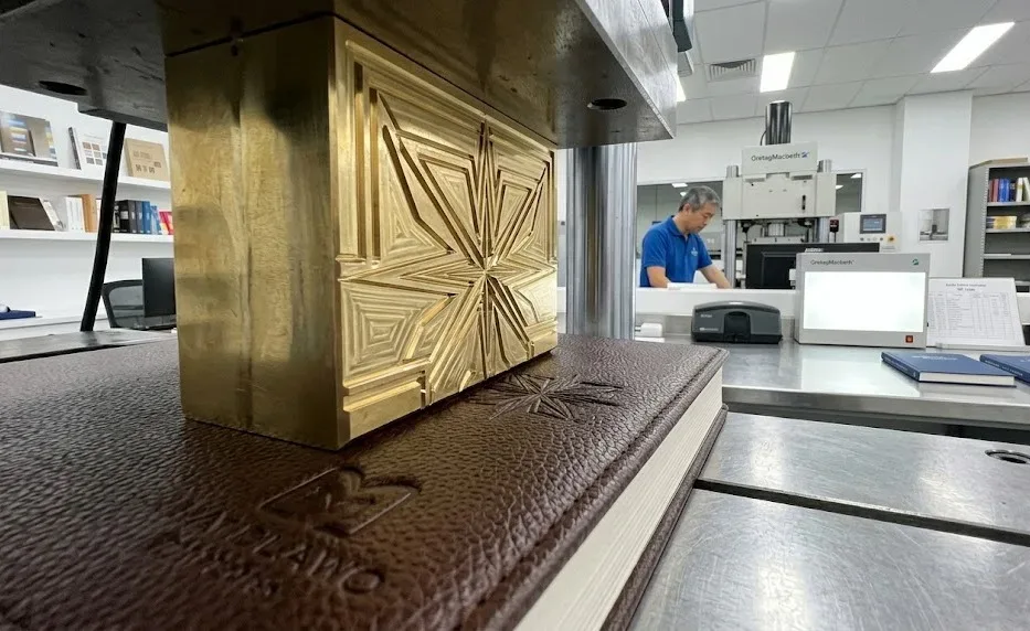 Primer plano macrotécnico de un troquel de latón grabado por CNC que presiona un intrincado motivo de estrellas en una funda de cuero PU termo reactivo e1779492651121 Un primer plano macrotécnico de un troquel de latón grabado por CNC que presiona un intrincado motivo de estrellas en una funda de cuero termoplástico PU reactivo al calor.